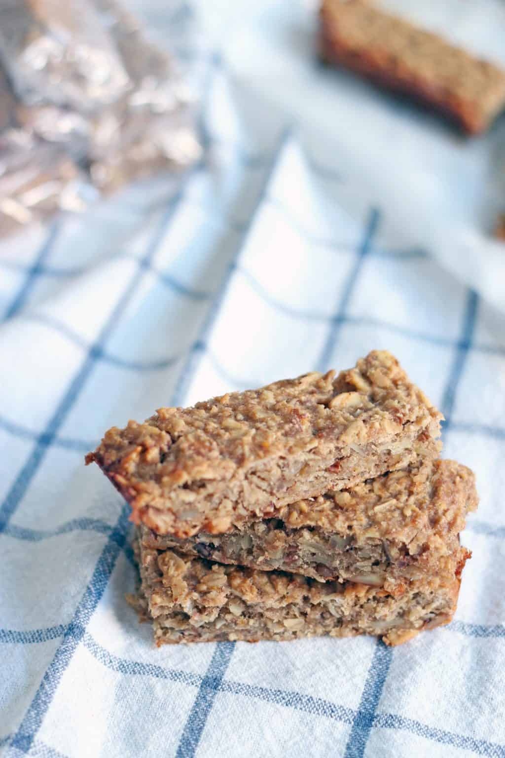 Three peanut butter and banana energy bars in a stack on a blue and white checkered cloth.