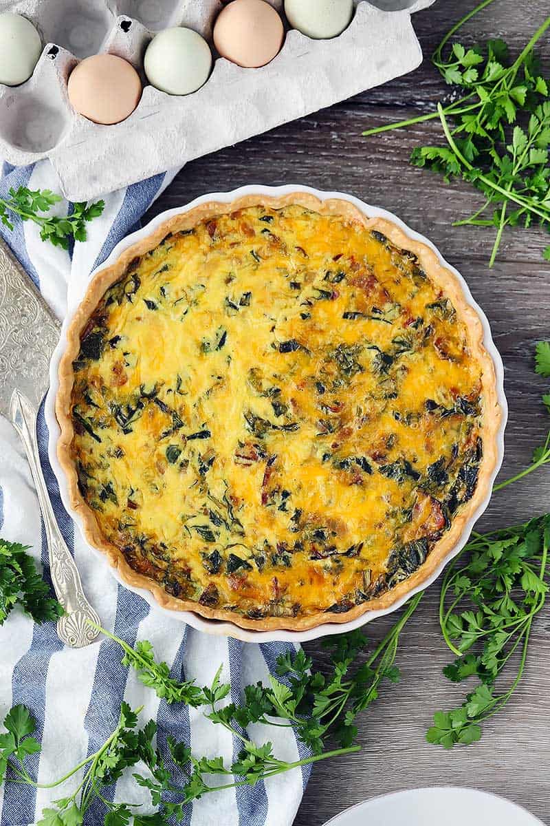 Overhead photo of a quiche with an egg carton.