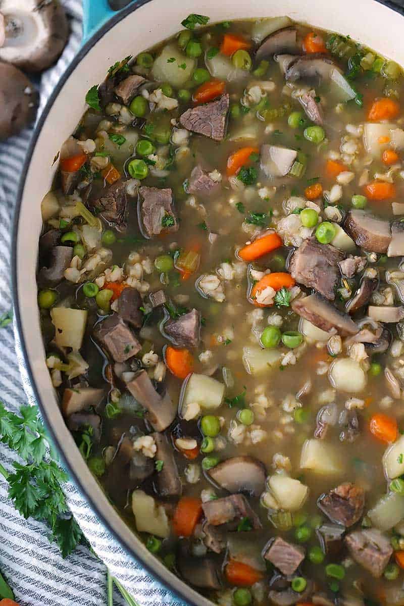 Close up photo of beef barley and mushroom soup in a Dutch oven.