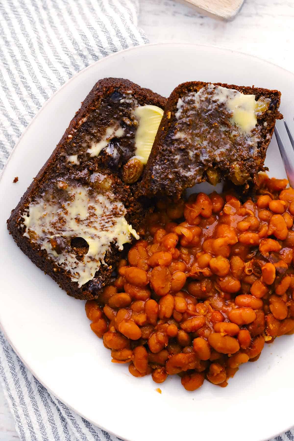 Overhead photo of two slices of brown bread and beans on a white plate.