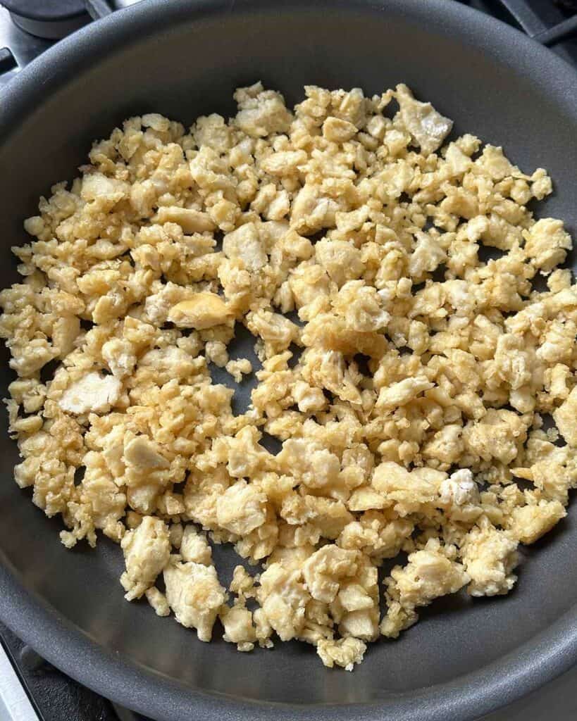 Cooking cornstarch coated torn tofu in a skillet.