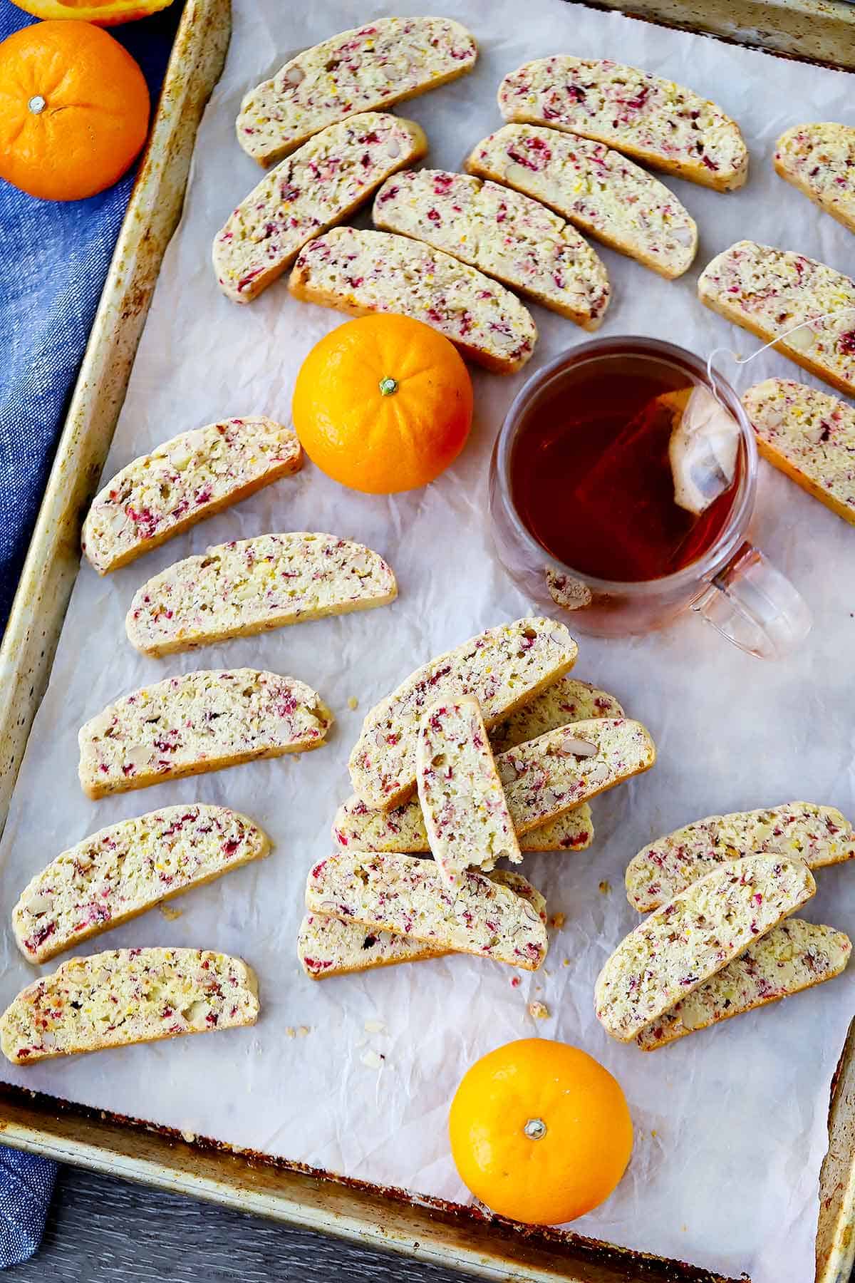 A baking sheet with cranberry orange biscotti and a cup of tea.