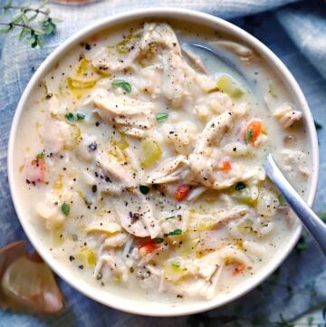 Square photo of creamy chicken and rice soup in a white bowl, overhead view, with a spoon.