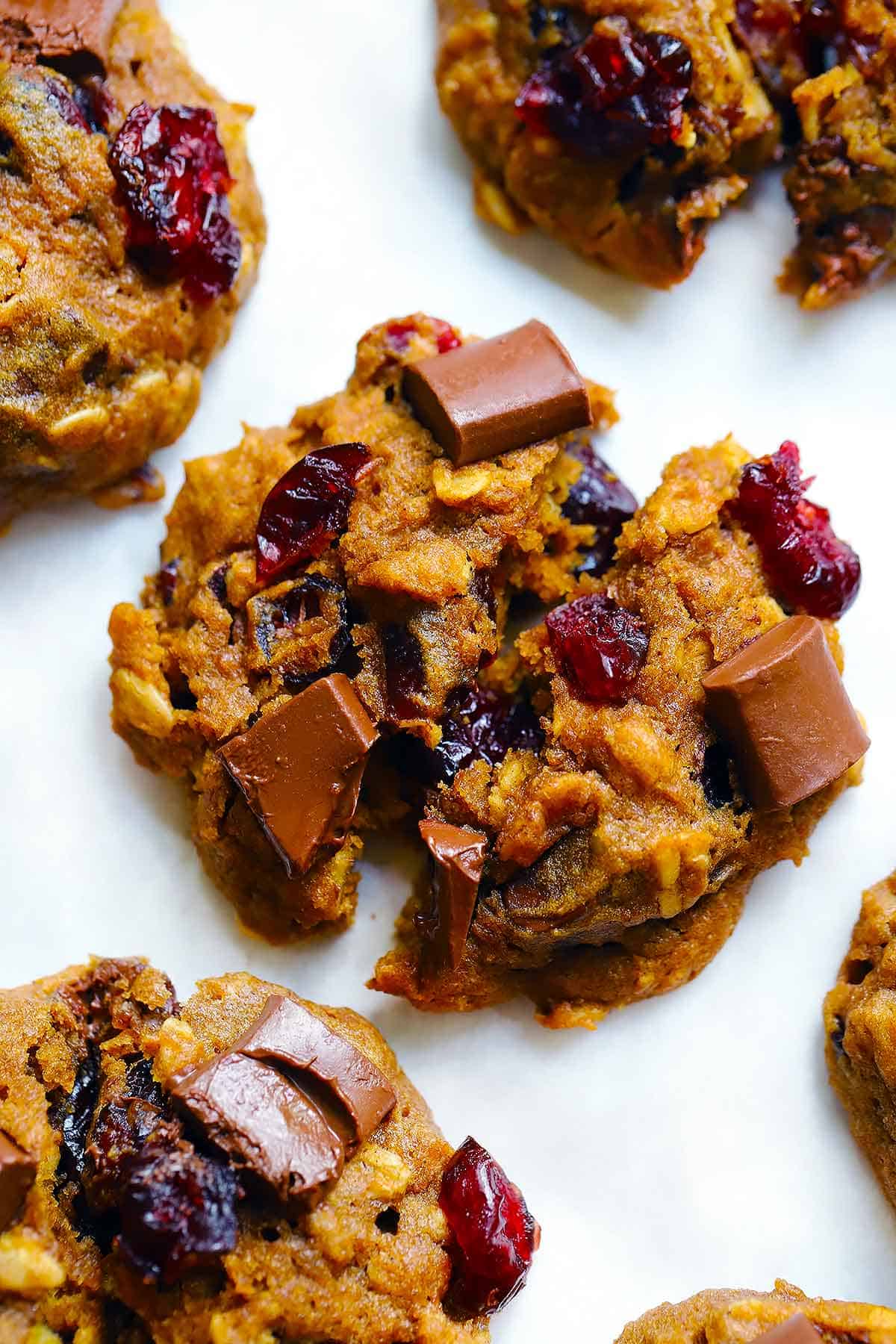 Close up photo of a healthy pumpkin oatmeal cookie with chocolate chunks and dried cranberries broken in half.