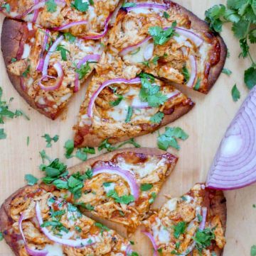 Bird's eye view of two BBQ Chicken Naan Pizzas on a wooden cutting board.