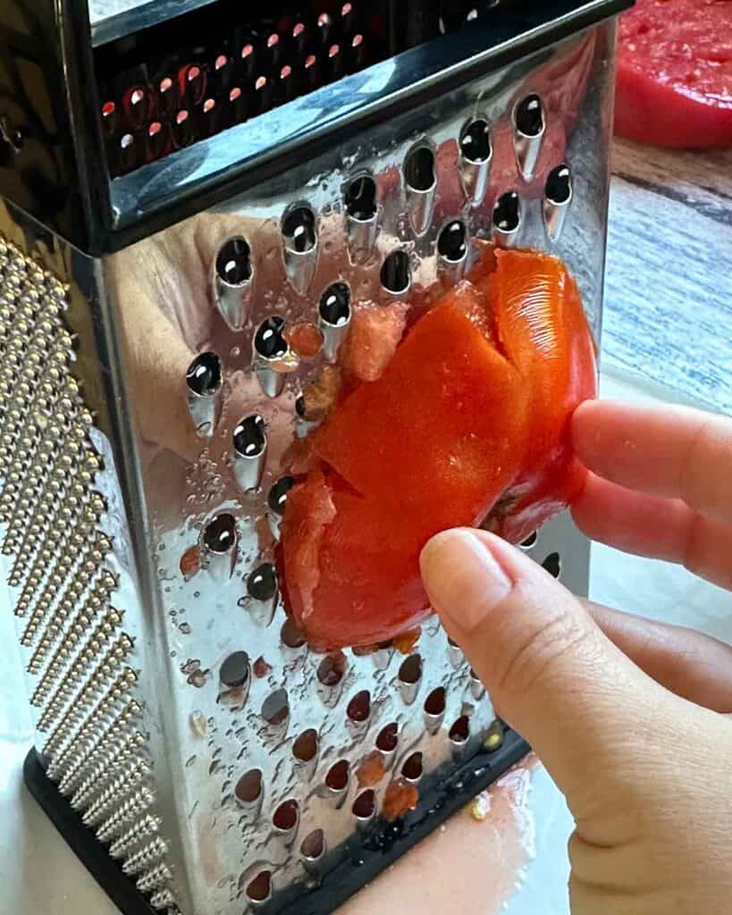 Grating half a tomato on a box cutter.