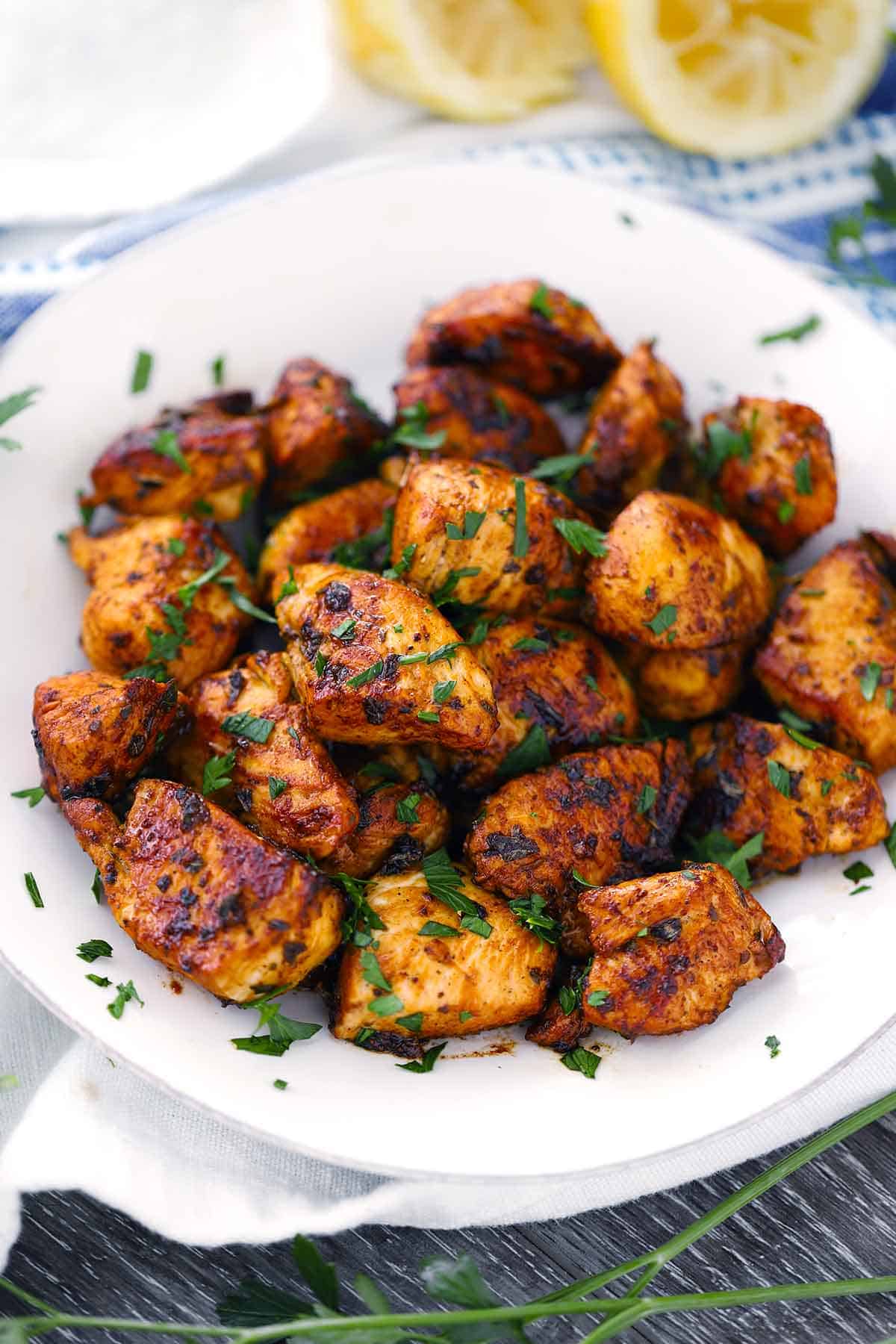 Greek Chicken bites on a white plate garnished with parsley.