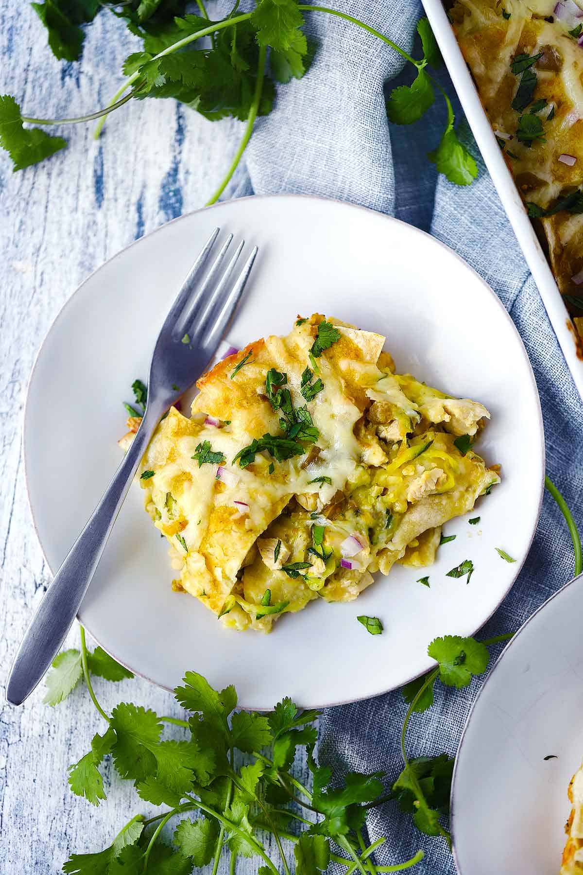 Overhead photo of a white plate with a piece of green chicken enchilada casserole.