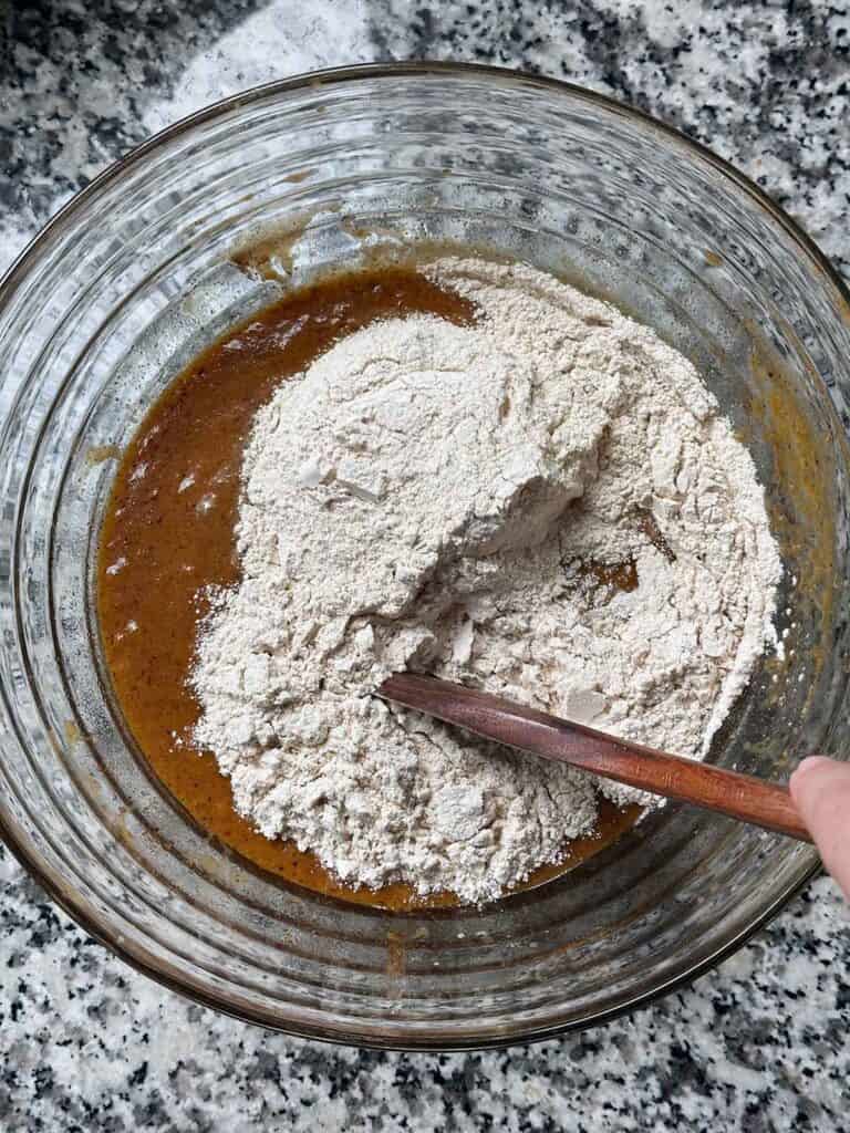 Adding whole wheat flour to the bowl to make batter for healthy pumpkin bread.