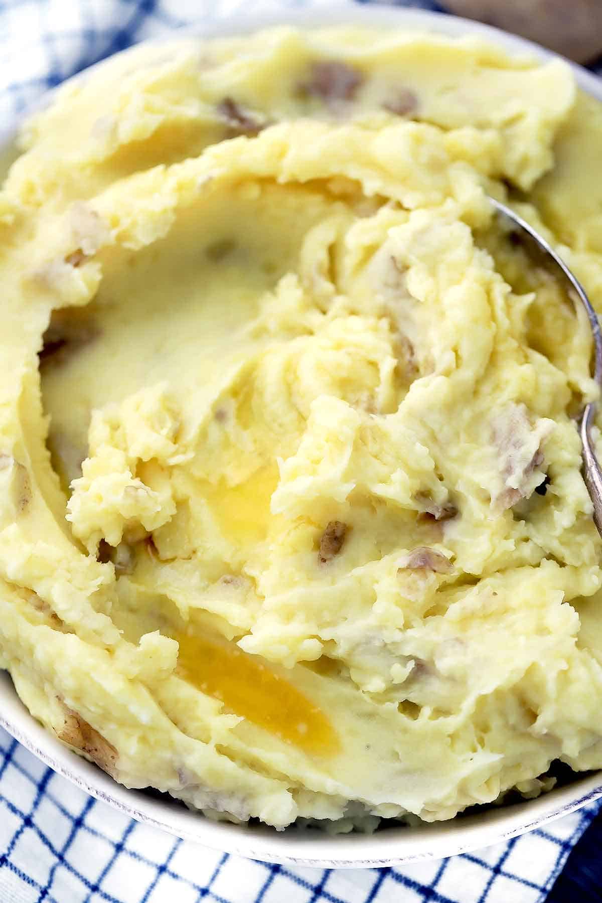 A close up photo of homemade mashed potatoes with butter melted on top.