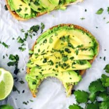 A piece of avocado toast with a bite taken out.