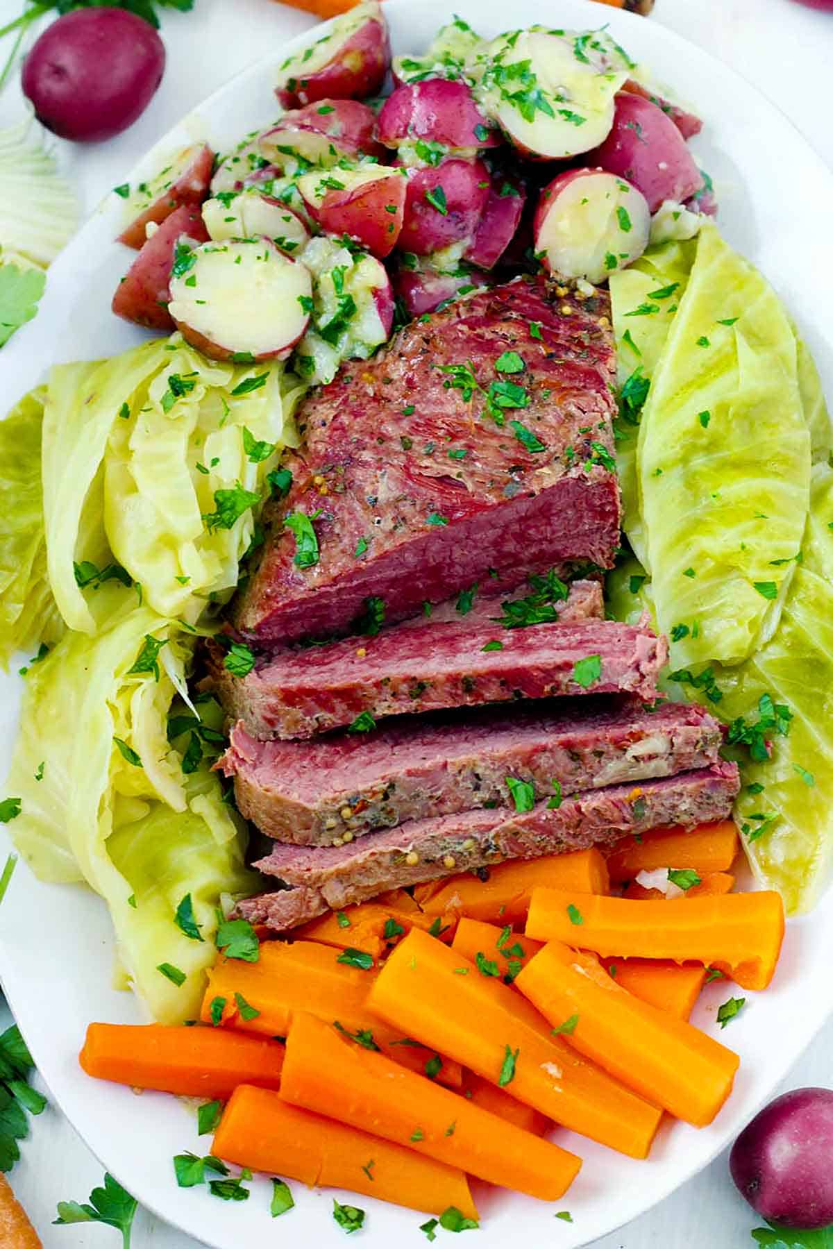 Overhead photo of a platter with corned beef, cabbage, carrots, and buttered potatoes.