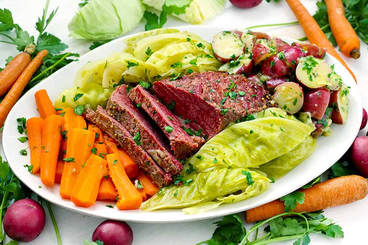 Horizontal photo of a platter of Irish boiled dinner, corned beef, cabbage, and carrots and potatoes.