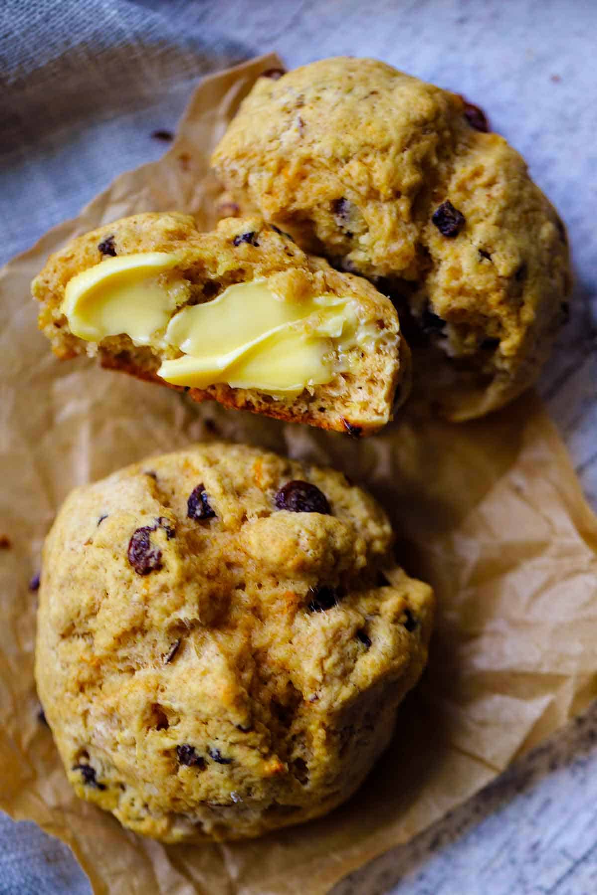 Close up of Irish soda bread scones, with one torn in half and spread with butter.