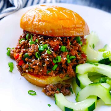 Square photo of korean bbq sloppy joe with cucumber salad on side.
