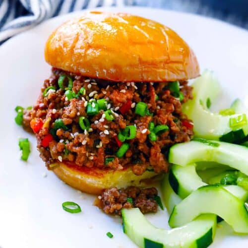 Square photo of korean bbq sloppy joe with cucumber salad on side.