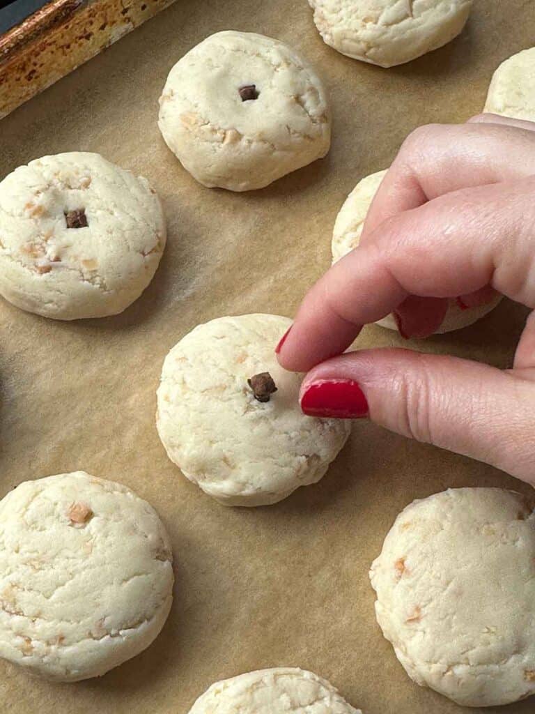 Adding a whole clove to kourabiedes cookies before baking.