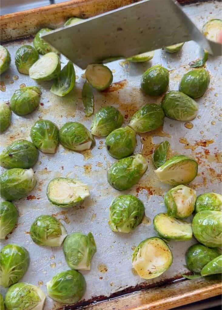 Spreading Brussels sprouts out evenly on a baking sheet before roasting.