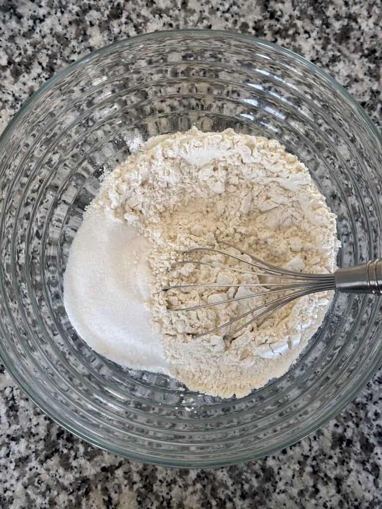 Whisking together flour, sugar, baking powder, and salt in a large bowl.