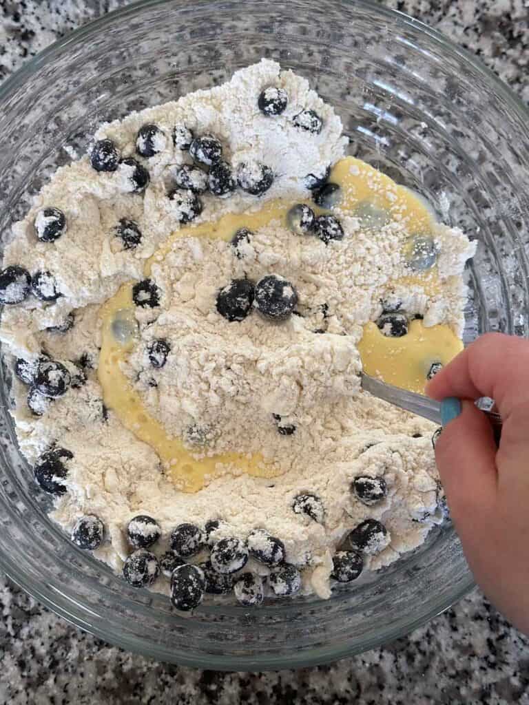 Stirring eggs and milk into a butter and flour mixture for mini blueberry scones.