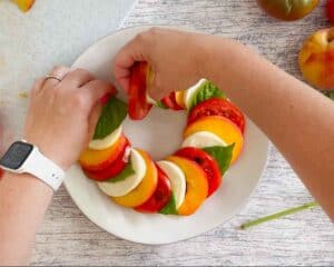 Tucking the final layer of a caprese salad in a circular shape under the first layer.