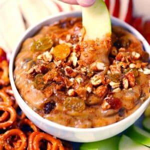 Square photo of an apple slice dipped in peanut butter dip.