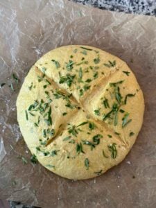 A loaf of pumpkin no knead bread with rosemary on top before baking.