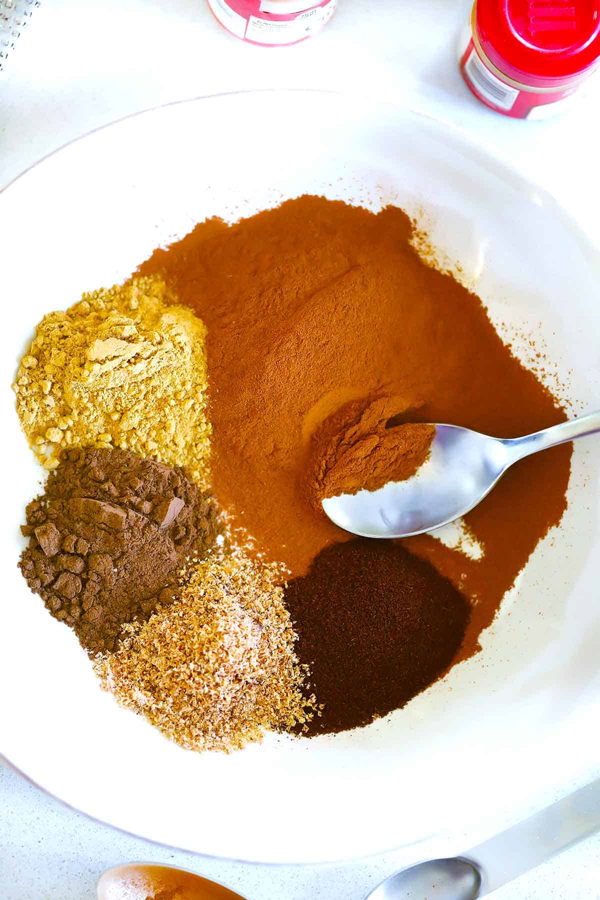Cinnamon, nutmeg, allspice, ground cloves, and ginger in a bowl.