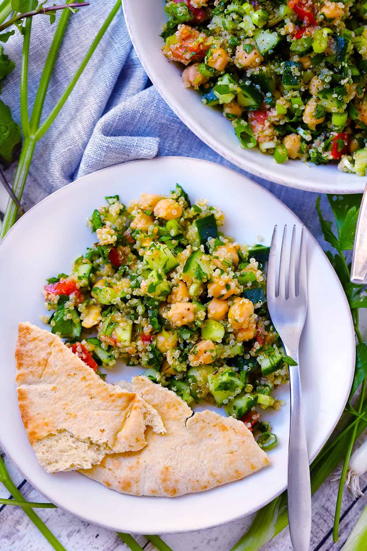A white plate with pita bread and a serving of tabbouleh salad on it.