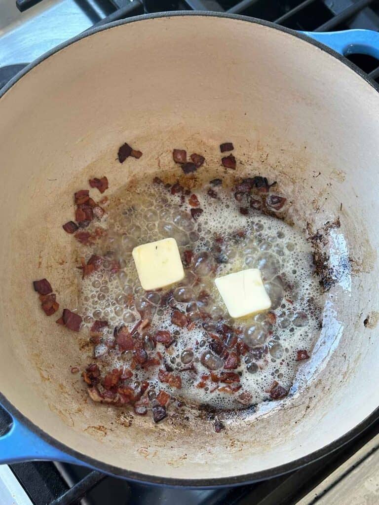 Adding butter to chopped bacon in a Dutch oven.