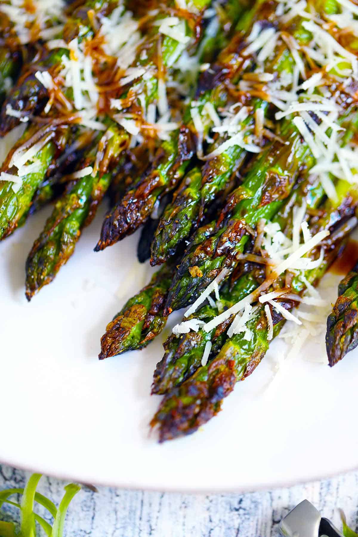 Close up photo of the crispy tips of roasted asparagus topped with parmesan cheese and balsamic vinegar.
