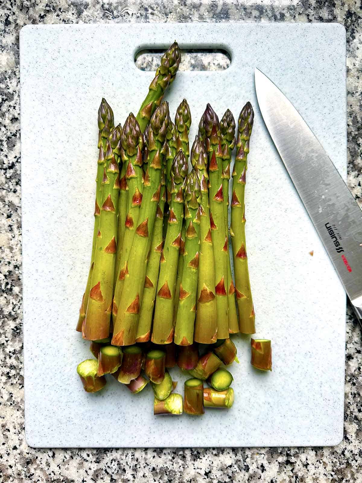 Overhead photo of asparagus spears on a cutting board with about a half inch of the very end cut off.