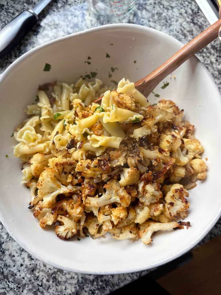 Mixing roasted cauliflower, onions, and crispy breadcrumbs with pasta.