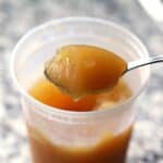 Square photo of a spoonful of cold bone broth that has gelled up from the collagen.