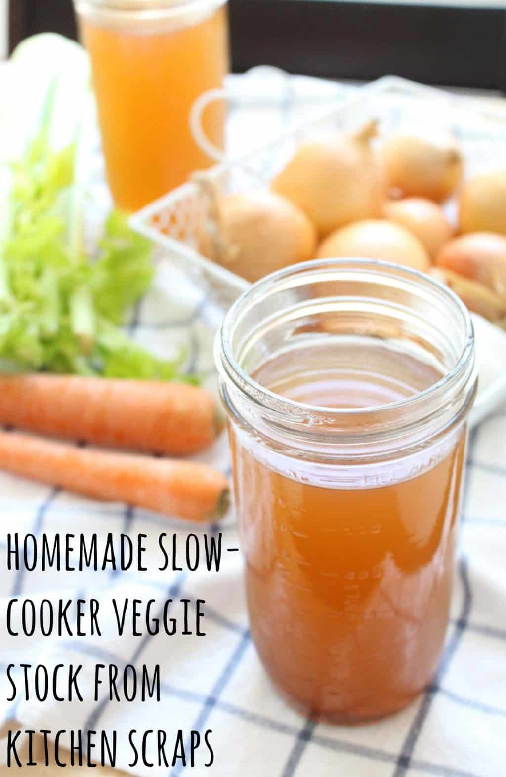 Glass jar full of vegetable stock on a blue and white checkered tablecloth, with vegetables in the background. Overlaid text reads: Homemade slow-cooker veggie stock from kitchen scraps.