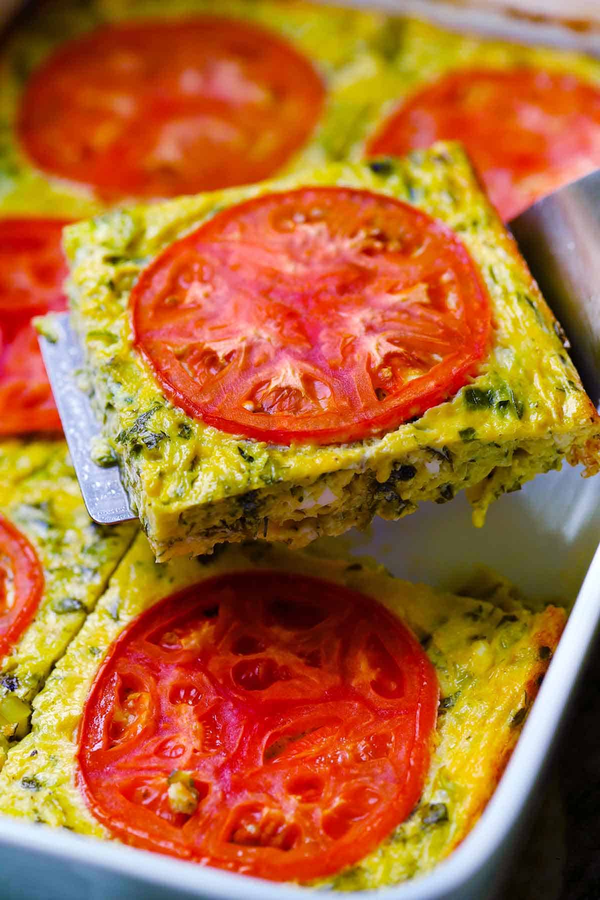 A spatula lifting out a slice of greek zucchini casserole.