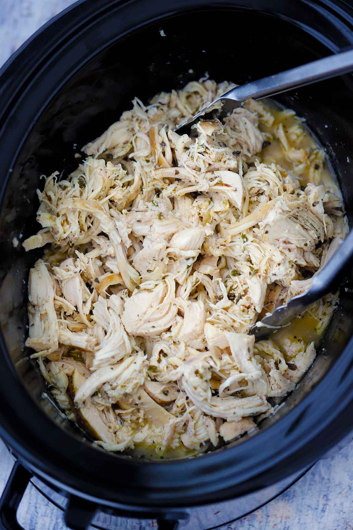 Cooked shredded chicken in a slow cooker crock.