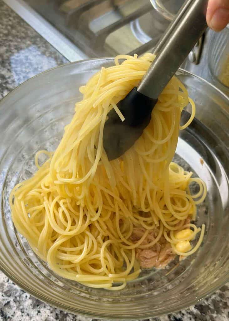 Tossing warm spaghetti with olive oil packed tuna and butter.