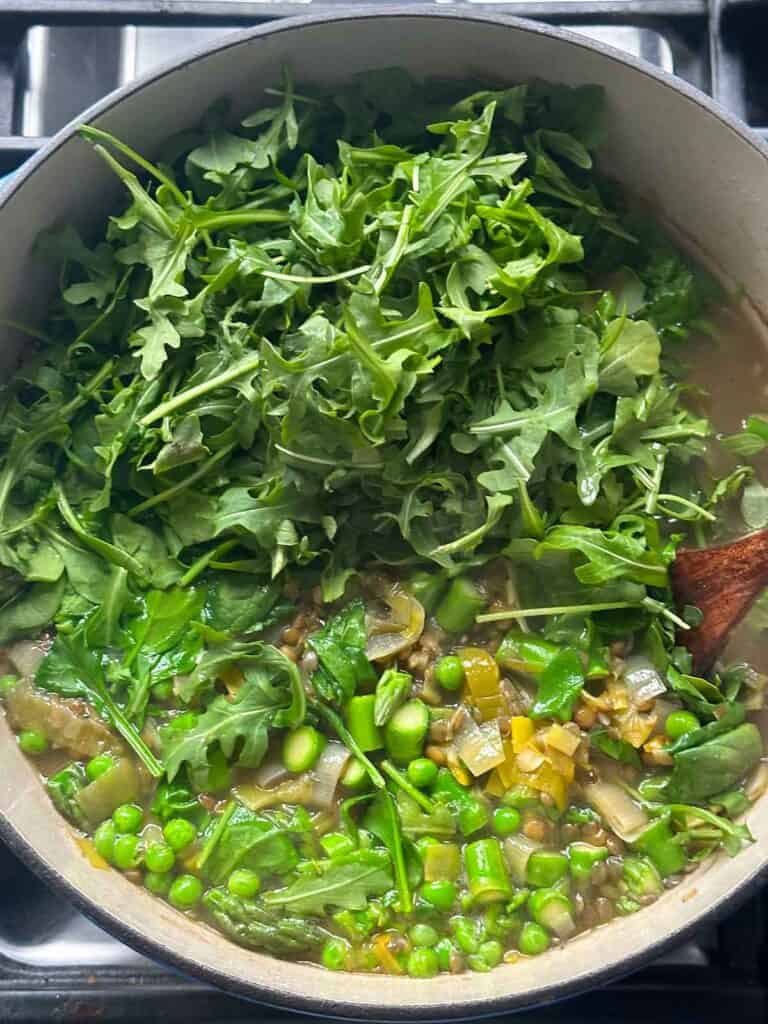 Adding arugula, spinach, asparagus, and peas to spring lentil vegetable soup.