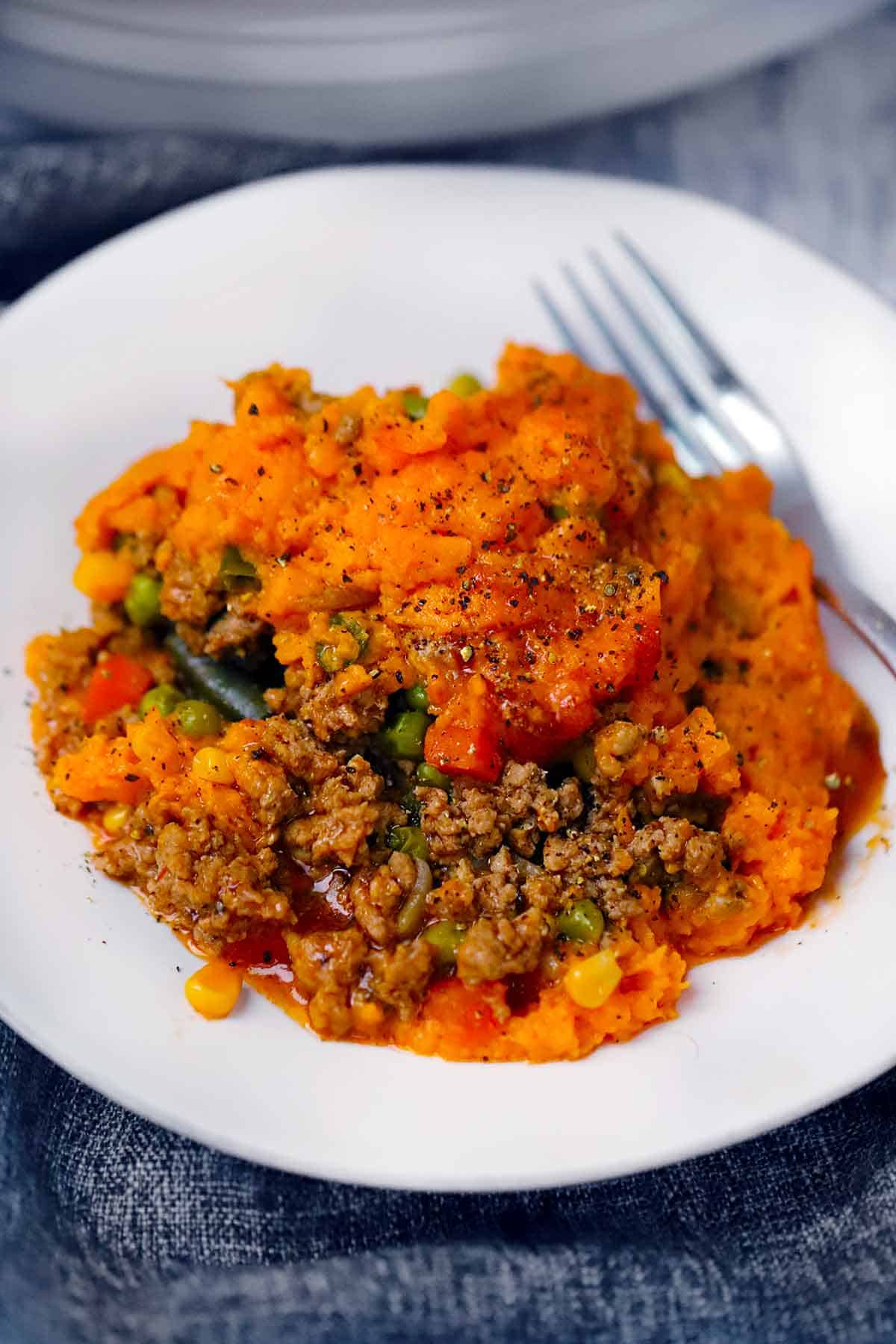 White plate with a serving of sweet potato shepherd's pie and a fork on it.