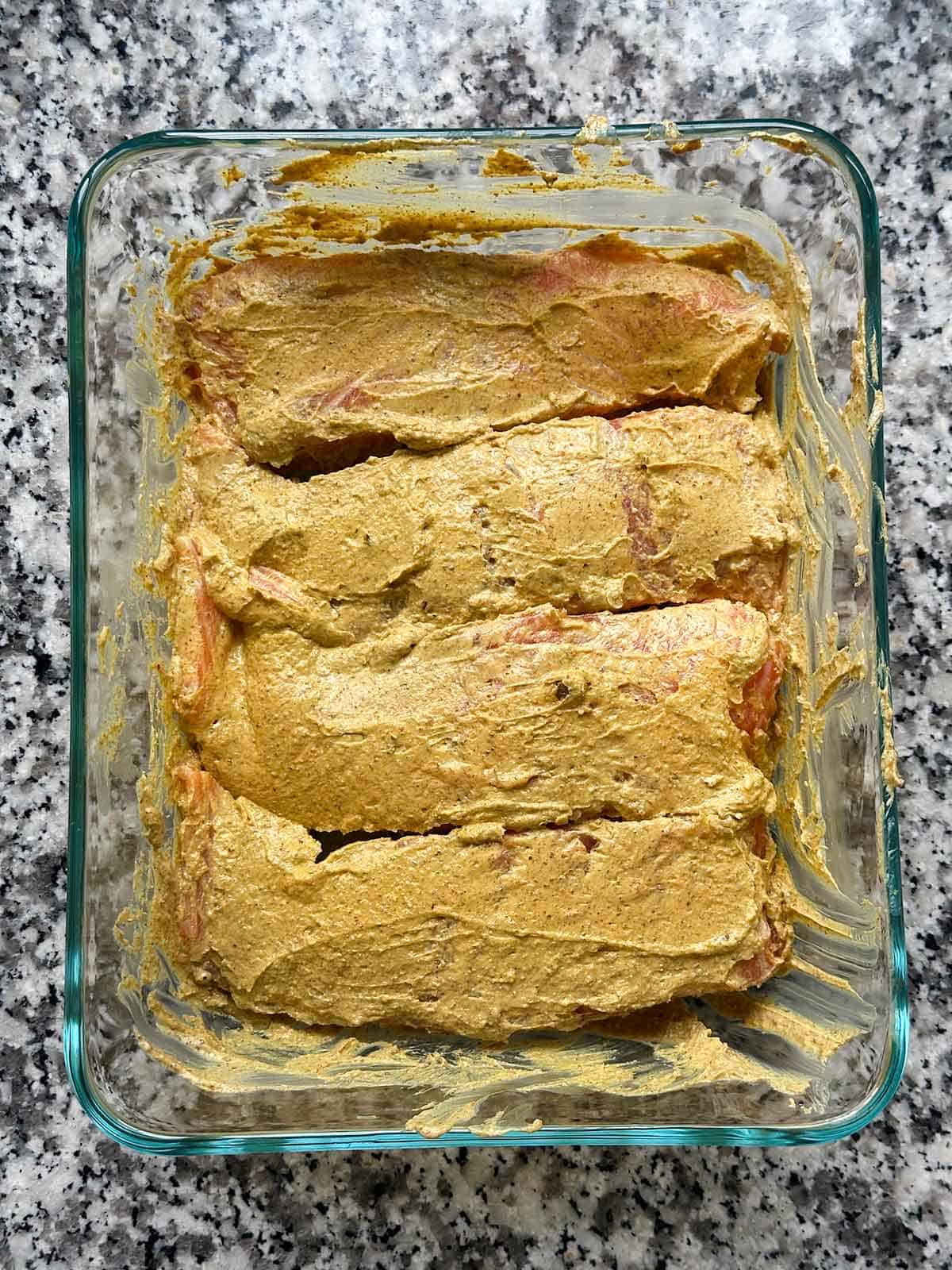 Salmon filets being marinated in a tandoori spiced yogurt mixture.