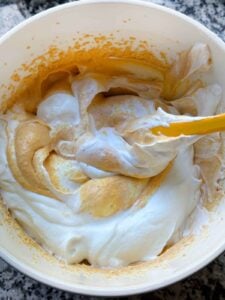 Folding together whipped cream with a pumpkin puree and mascarpone cheese mixture.